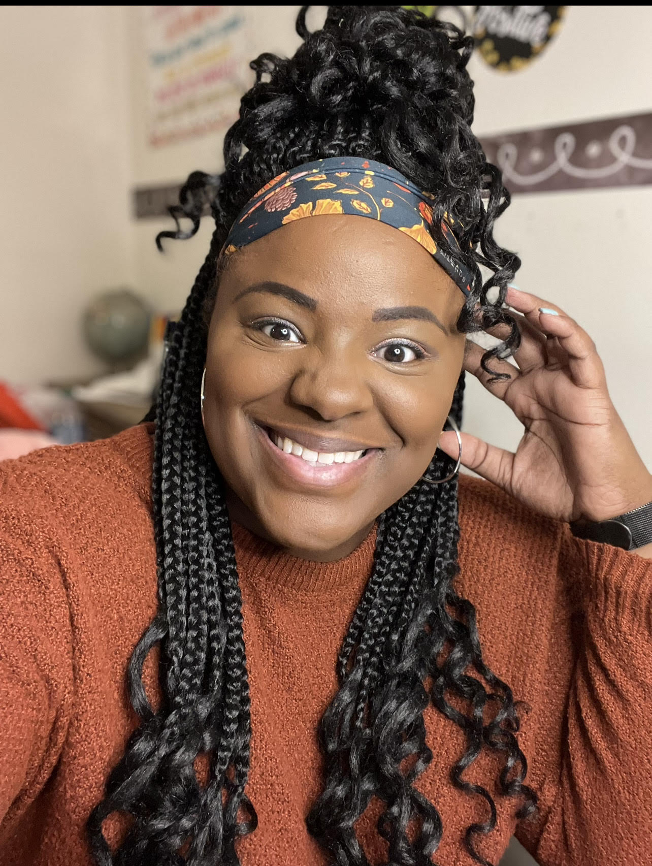 Picture of Briana Richardson, a Black woman with braids and wearing an orange sweater, smiling